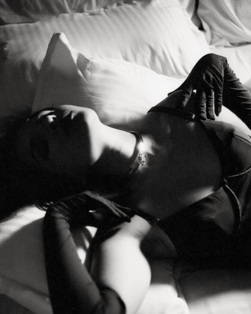 Person lying on a bed with a pillow, black and white photo
