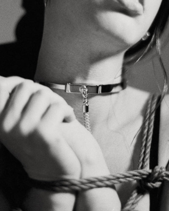 Black and white photo of a person bound with rope against a plain background